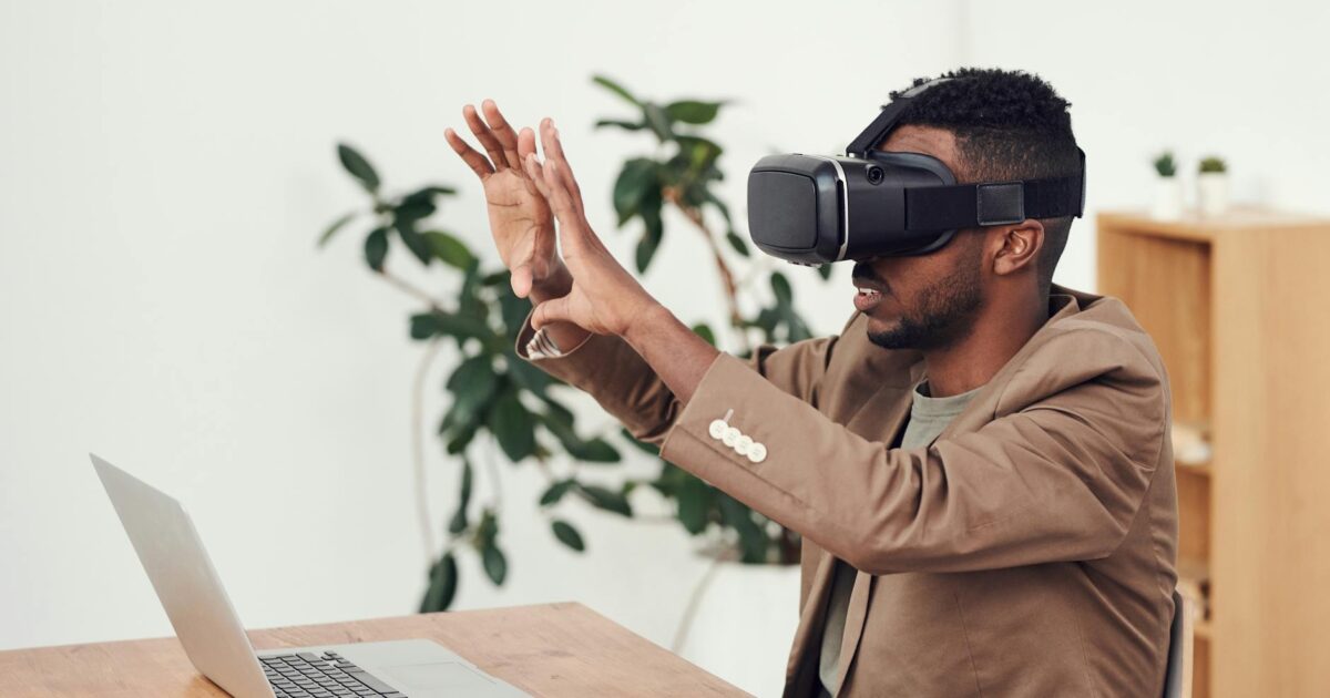 Man using a VR headset in an office with a laptop, engaging with virtual content.