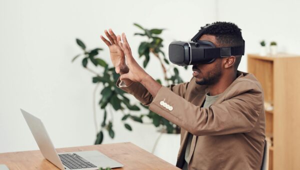 Man using a VR headset in an office with a laptop, engaging with virtual content.