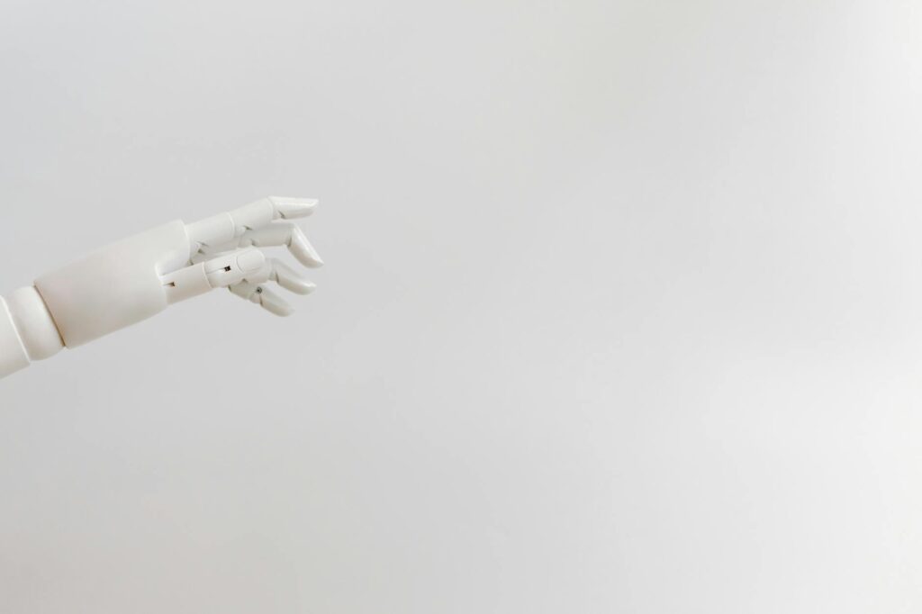 Minimalist image of a robotic hand reaching out on a white background.