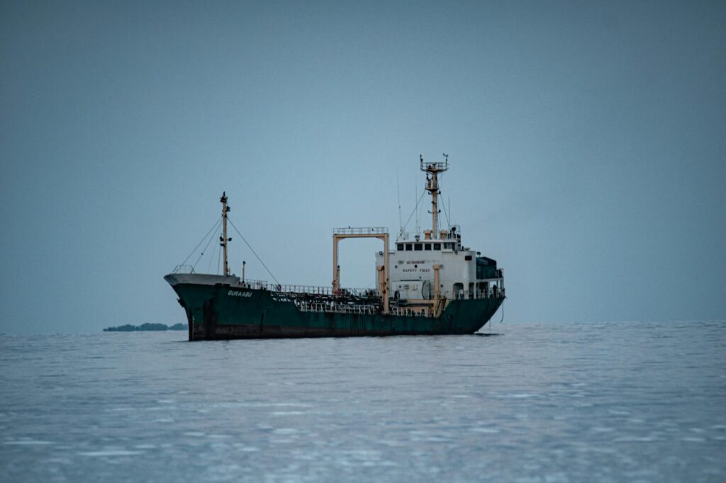 A cargo ship named Gualjan anchored on a calm sea under overcast skies.