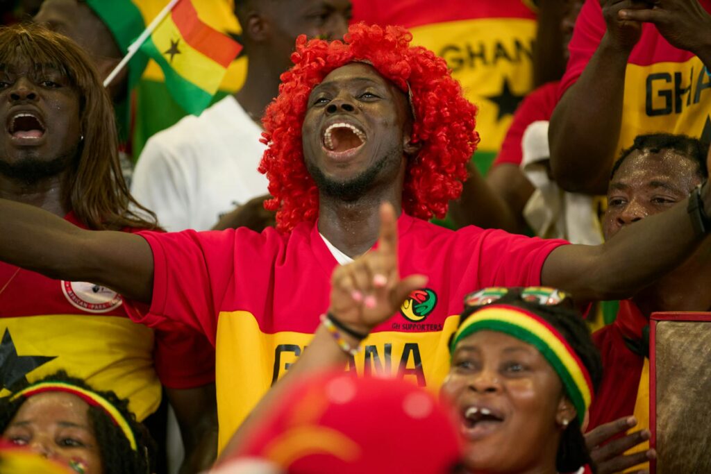 Ghanaian soccer fans passionately cheering during a match, showcasing national pride.