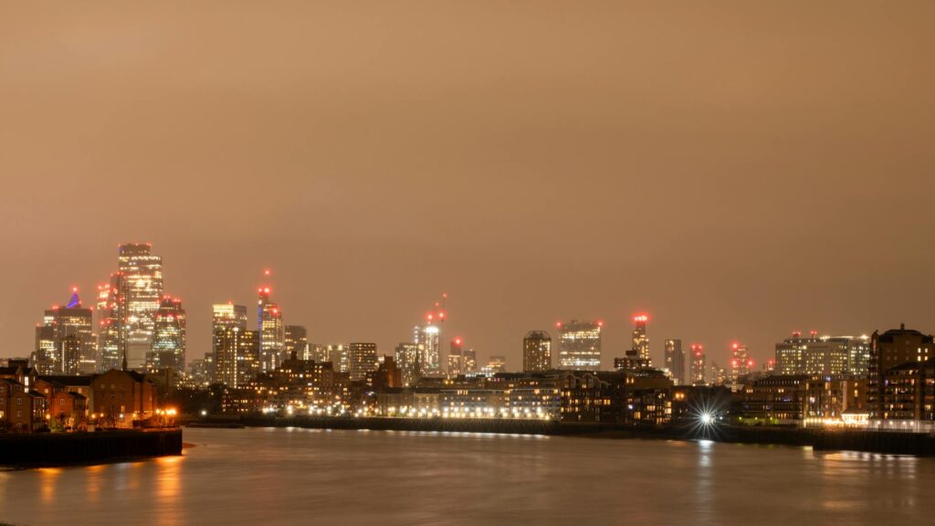 Stunning night view of London's skyline with the River Thames in the foreground, showcasing the city's illuminated towers.