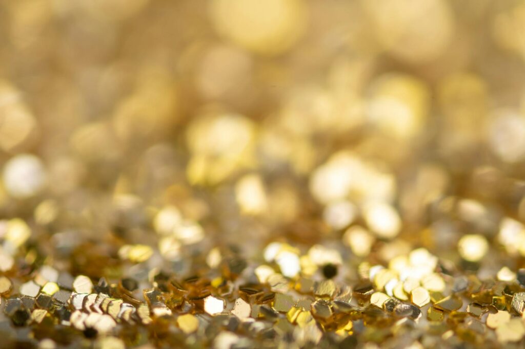 Selective focus of heap with shiny small yellow hexagon shaped sequins for golden decoration