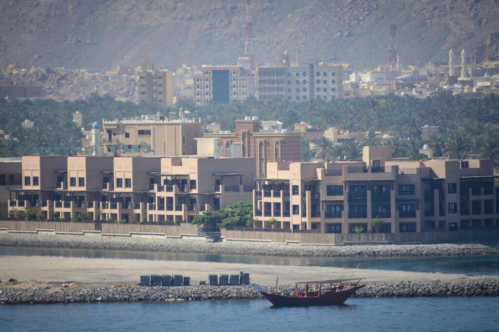 Contemporary buildings along the shore with a traditional dhow in al-Chasab, Musandam, Oman.
