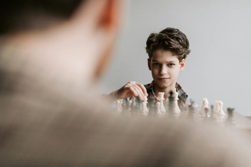 Young boy playing chess, captured in a strategic moment during an intense game indoors.