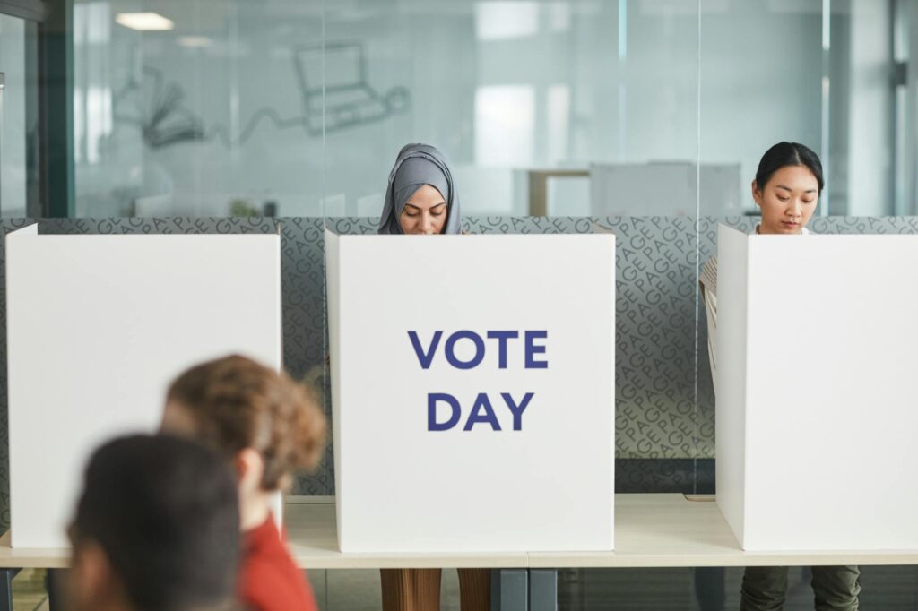 Two women casting their votes in an office during election day, focusing on diversity and civic engagement.
