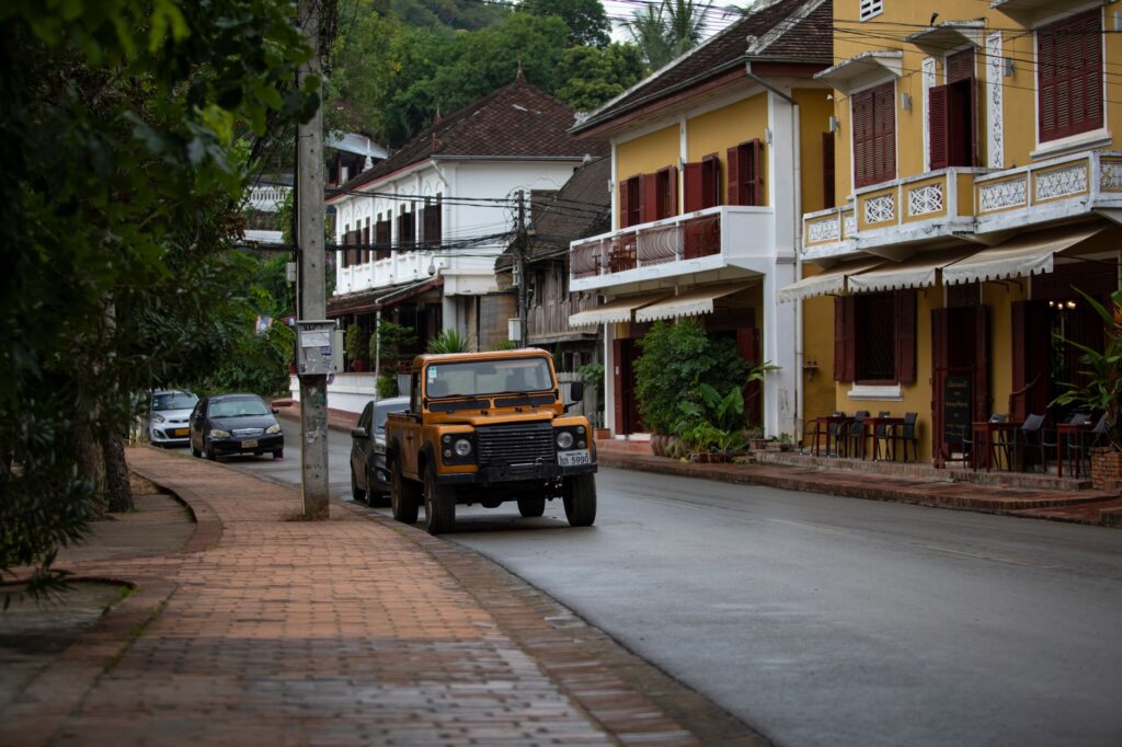 A classic Land Rover parked on a street lined with colonial architecture in Luang Prabang, Laos.