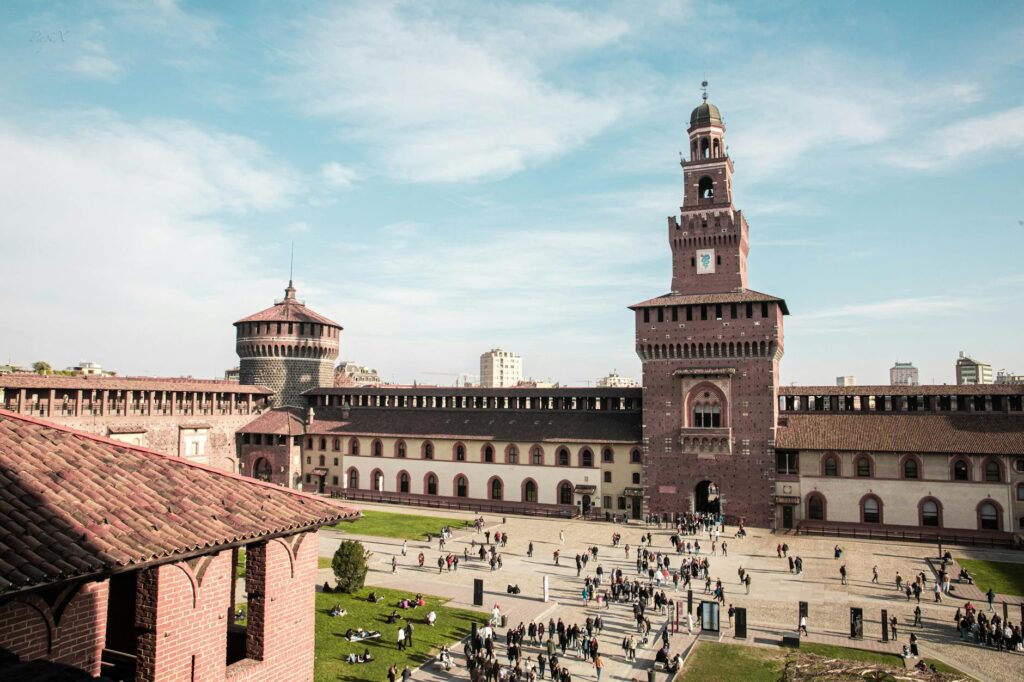 Aerial view of the historic Sforza Castle courtyard teeming with visitors in Milan, Italy.