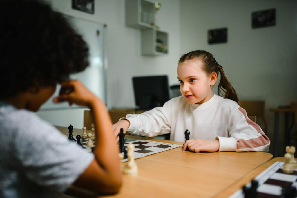 Two children engaged in a friendly chess match indoors, promoting strategic thinking.