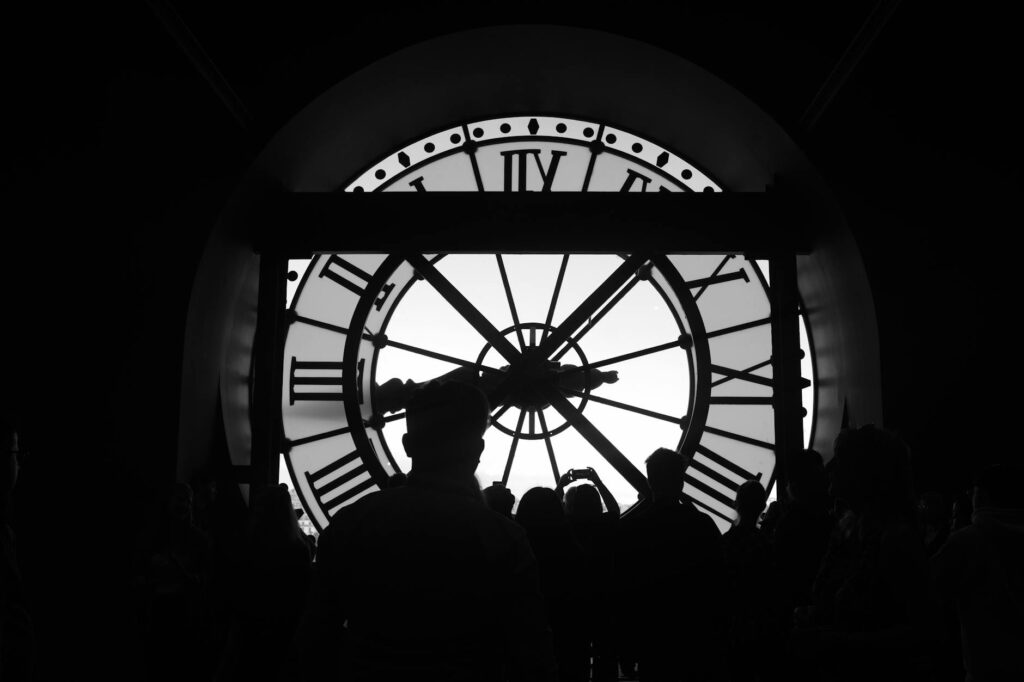 Silhouetted group in front of iconic Musée d'Orsay clock in Paris.