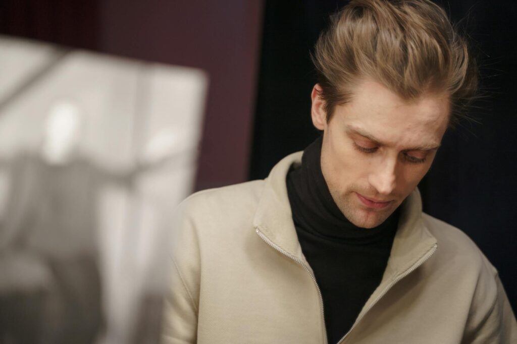 A thoughtful actor in a theater setting, deeply engaged in reviewing his script backstage.