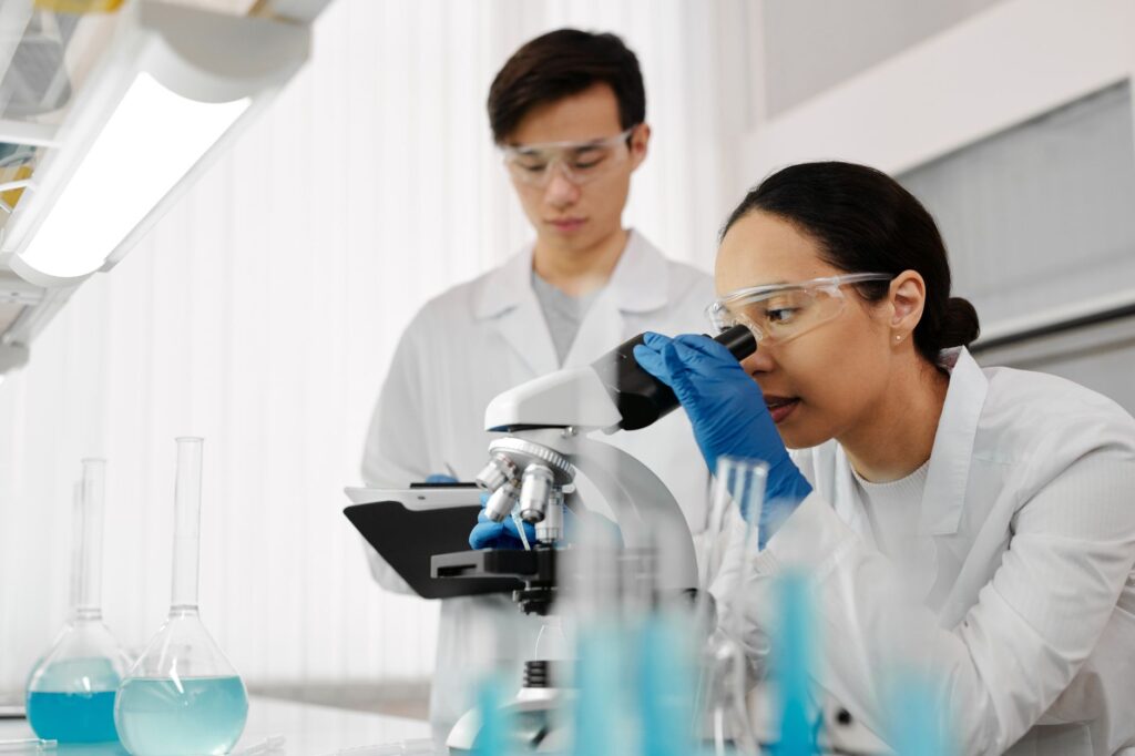 Two scientists in a laboratory using a microscope and analyzing samples.