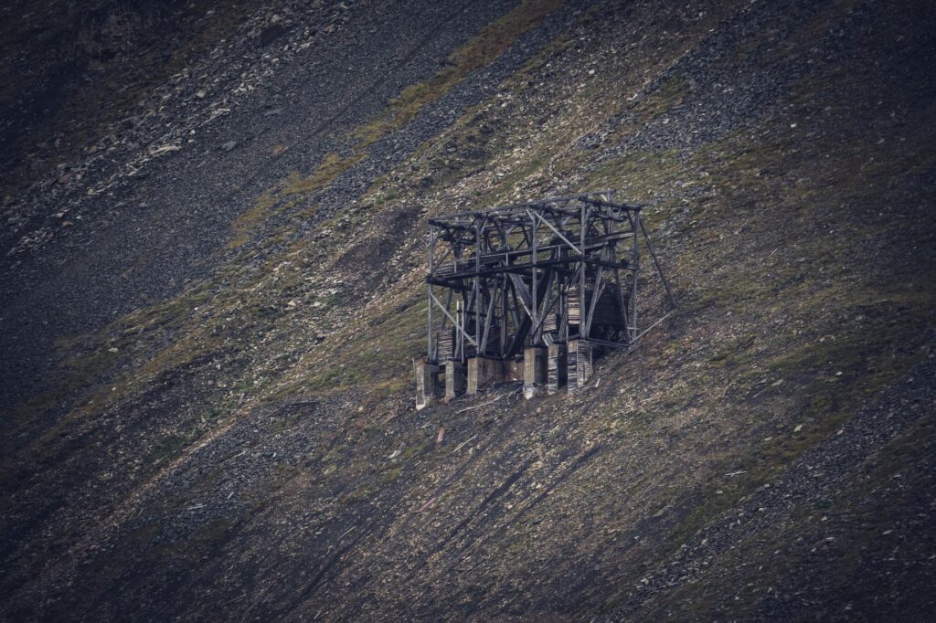 A vintage wooden mine structure on a barren rocky hill, showcasing a deserted rural landscape.