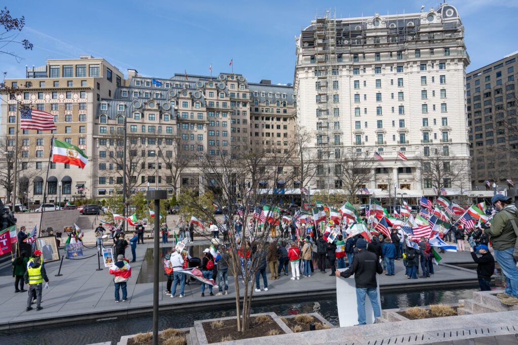 A vibrant demonstration with flags in Lafayette Square, Washington, DC with historic buildings in the background.