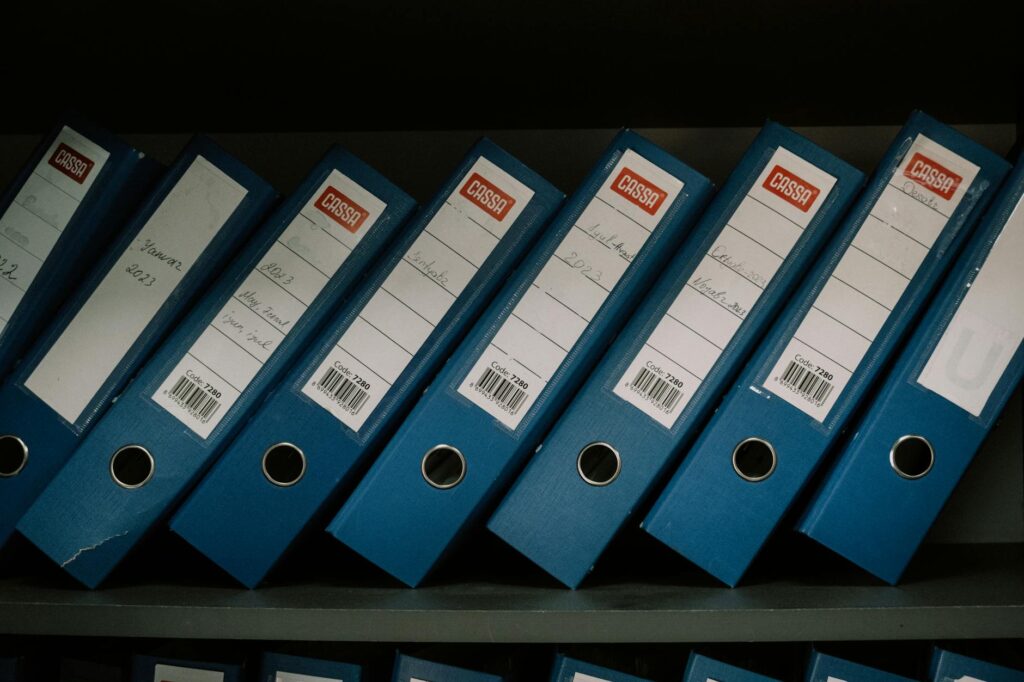 Neatly arranged blue office binders labeled with dates and names for organized storage.