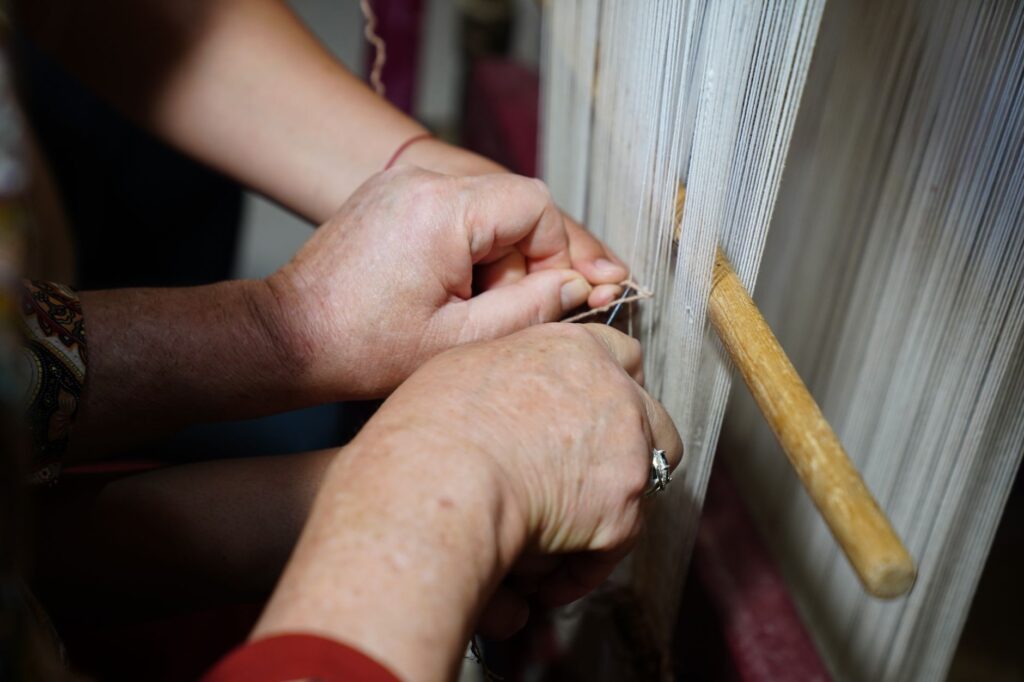 Skilled hands intricately weaving threads on a traditional loom. Textile craftsmanship at its finest.