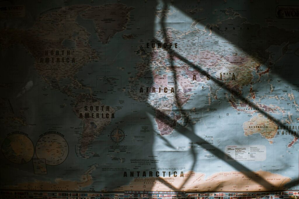 Aged world map with continents and oceans hanging on wall lit with sun