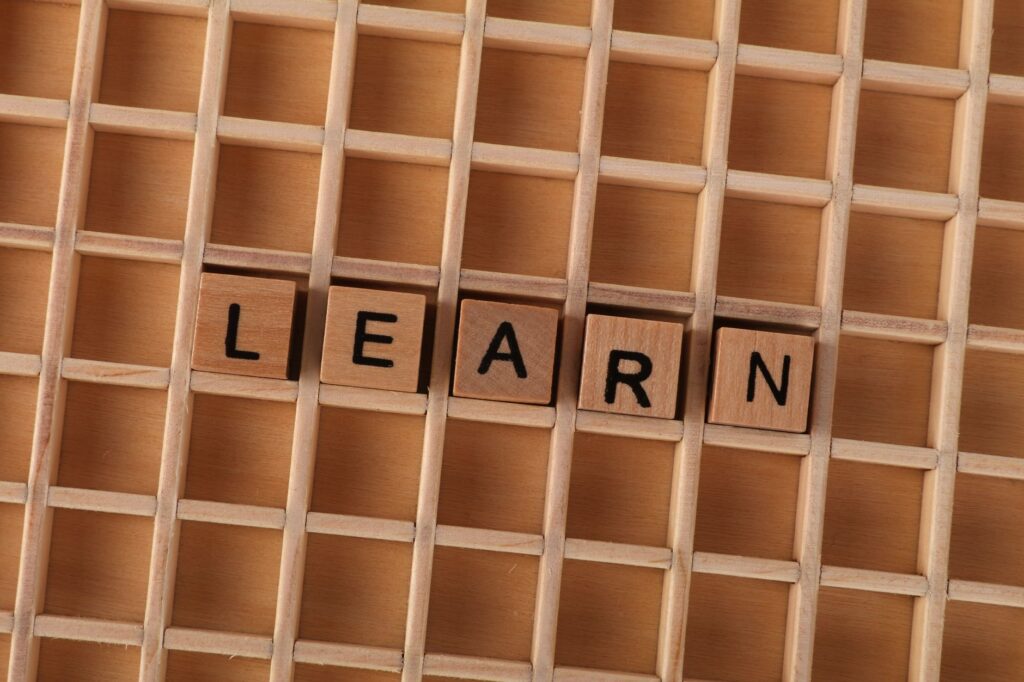 Wooden blocks spelling the word 'LEARN' on a grid-like wooden background. Educational concept.