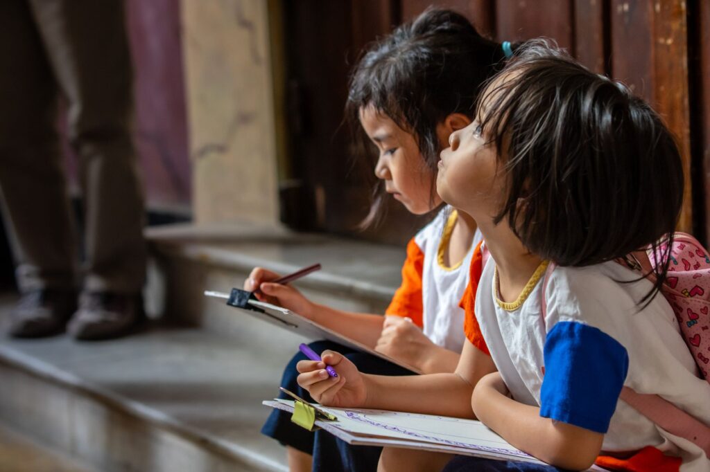Two young children absorbed in drawing indoors, showcasing creativity and concentration.