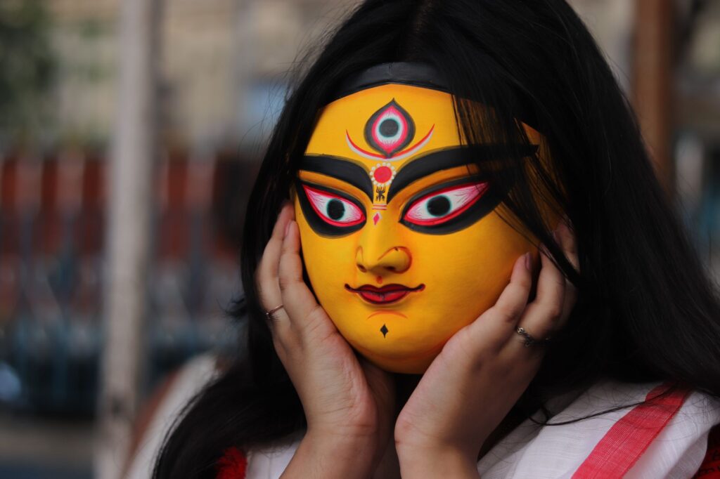 A vibrant portrait of a woman with a Hindu goddess mask in Kolkata, India.