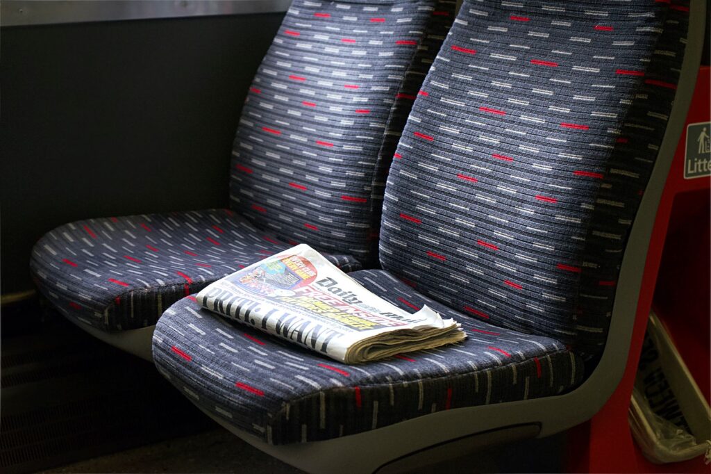 Close-up of empty bus seats with a newspaper, showcasing travel and leisure in the UK.