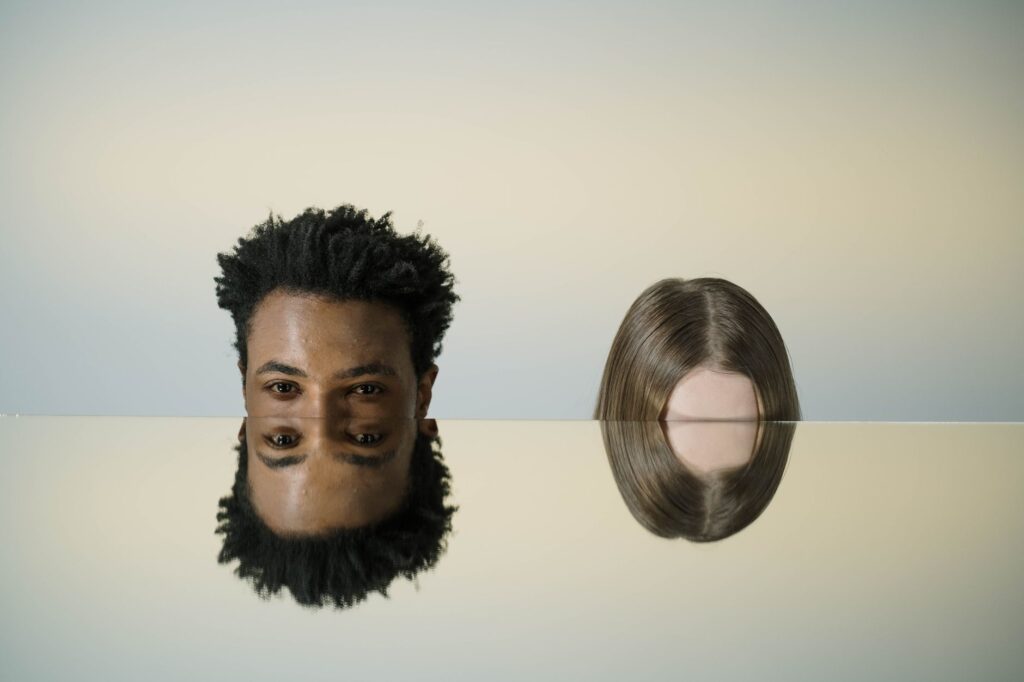 Artistic mirror portrait showing two heads with creative reflections, combining abstract elements and human interaction.
