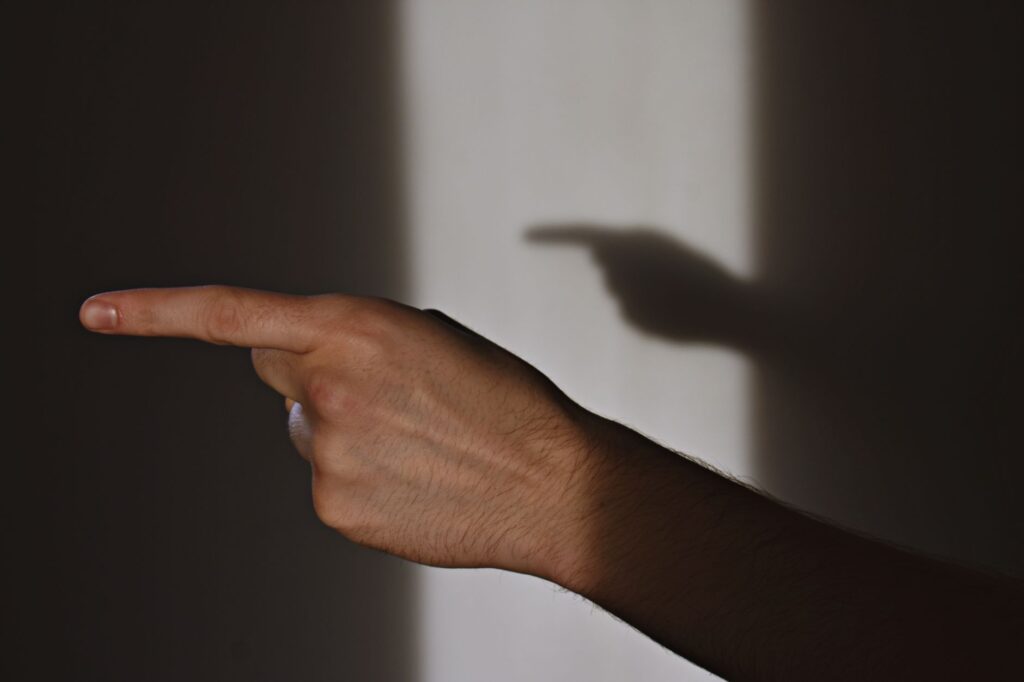 Close-up shot of a hand pointing, creating a shadow on a wall indoors.