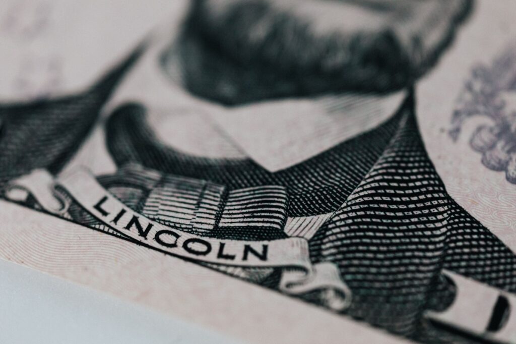 Crop of five dollar banknote with president Lincoln wearing costume on table