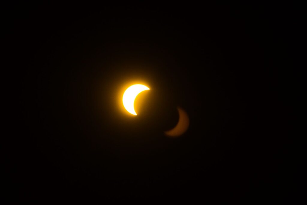 A mesmerizing partial solar eclipse with a glowing crescent amidst darkness.